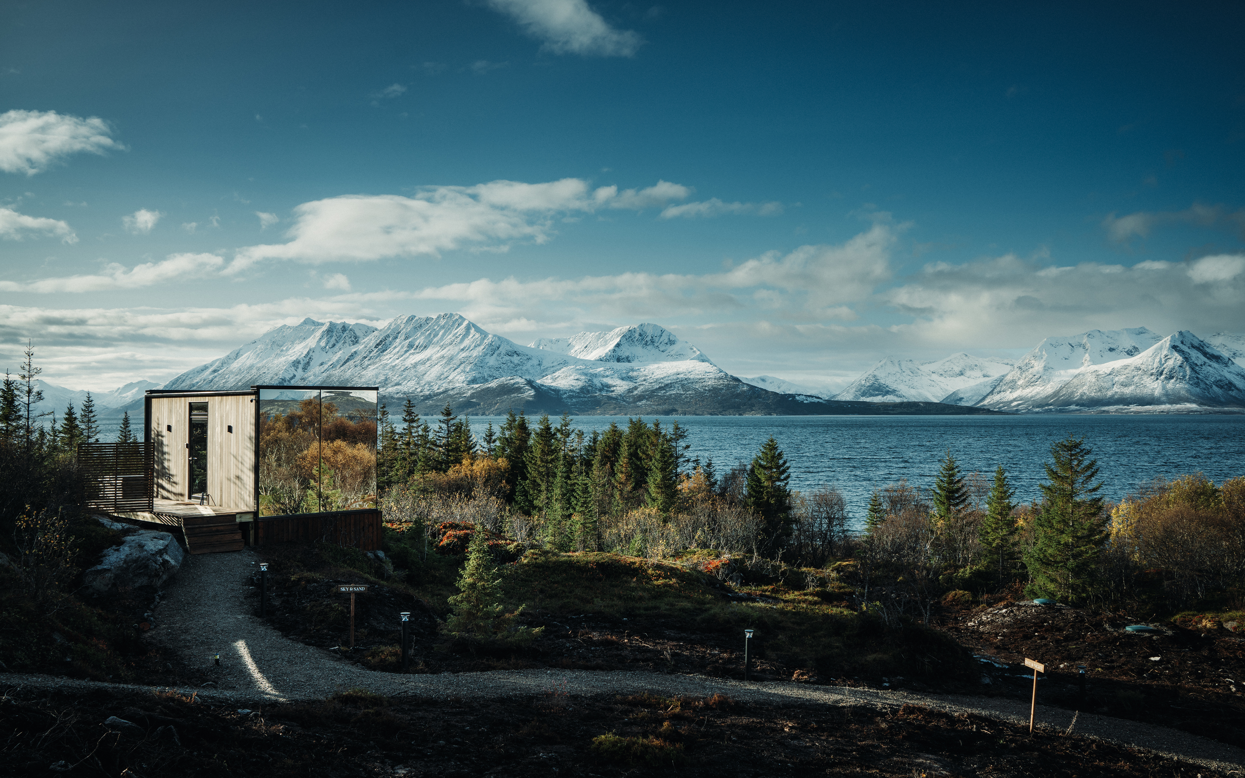 a house sits on a hill overlooking a lake with mountains in the background