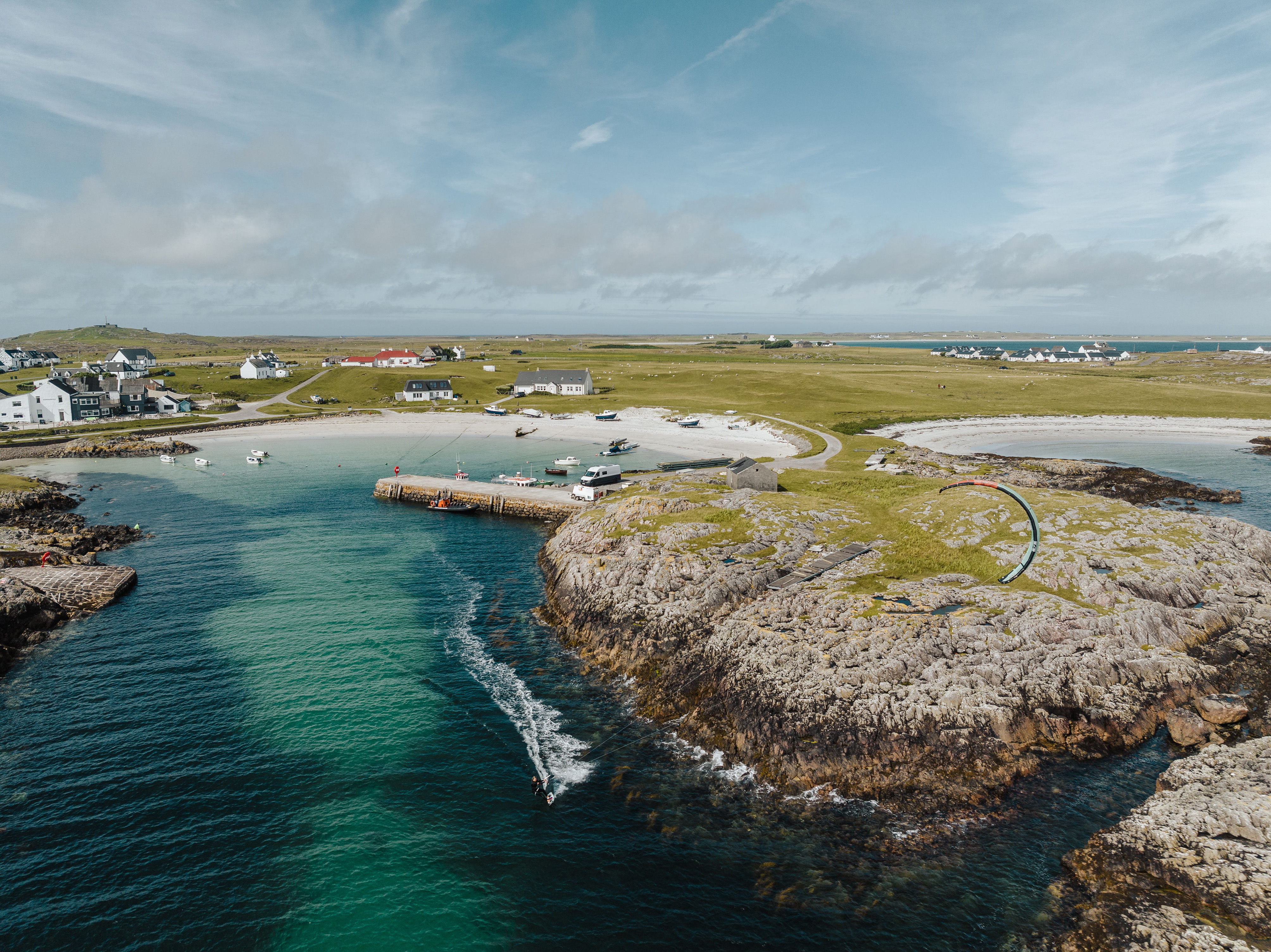 Aerial view of a sandy beach along Tiree island in Scotland with houses and a turquoise sea lagoon